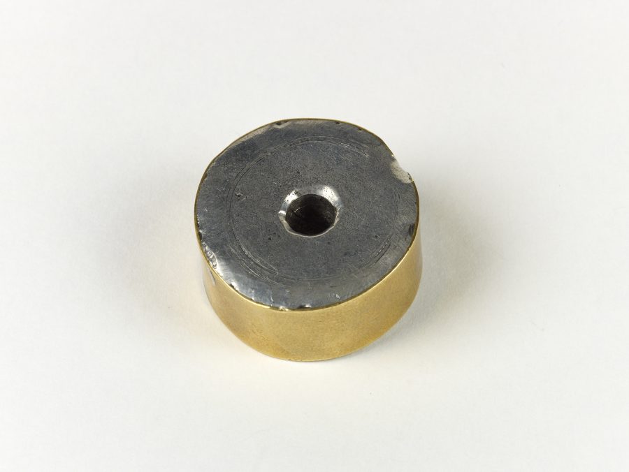 A circular weight edged with a copper alloy band