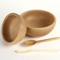Two carved wooden bowls with a bone and a wooden spoon