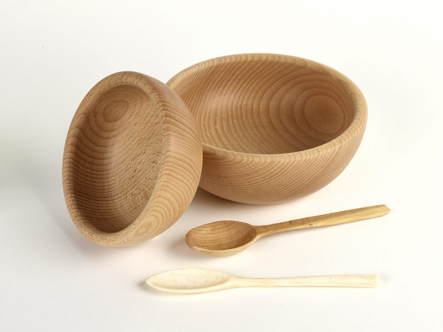 Two carved wooden bowls with a bone and a wooden spoon
