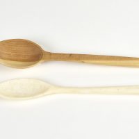A carved wooden spoon and a carved bone spoon