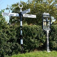 Signpost showing Kinoulton, Cropwell Bishop, Colston Bassett, Hickling Pastures, Nottingham, Long Clawson, Nether Broughton, Melton, and village sign of Hickling
